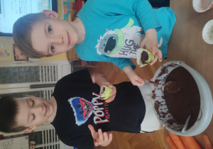 Dwaj chłopcy podczas nakładania ciasta do foremki.