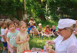 Pani nakładająca lody dzieciom stojącym w kolejce.