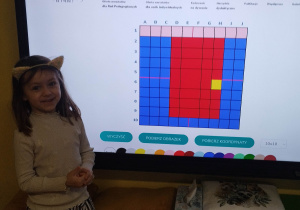 ziewczynka prezentuje własny rysunek na tablicy multimedialnej.