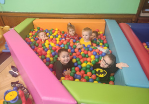 dzieci bawiące się w basenie z kolorowymi piłeczkami
